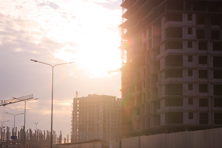 Construction of buildings and high-rise cranes against the evening sky