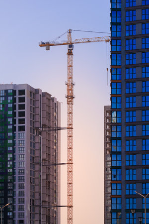 Construction of buildings and high-rise cranes against the evening skyの写真素材