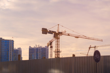 Construction of buildings and high-rise cranes against the evening sky