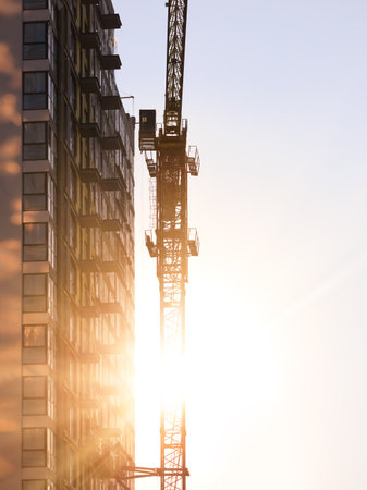 Construction of buildings and high-rise cranes against the evening skyの写真素材