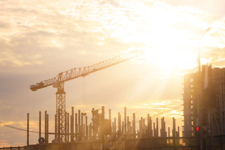Construction of buildings and high-rise cranes against the evening sky
