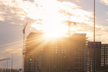 Construction of buildings and high-rise cranes against the evening skyの写真素材