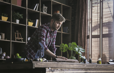 Young man leather worker hold new roll of leather on wooden table in work studioの写真素材