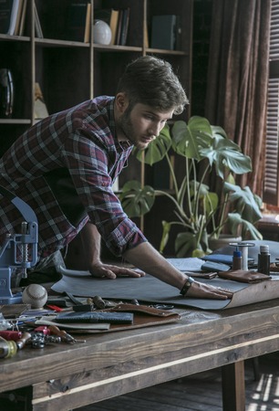 Young man leather maker begins work with piece of leatherの写真素材