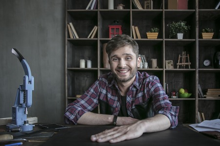 Small business owner. Leather worker sitting at working table and ready to workの写真素材