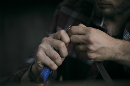 Close up of man hand leather manufacturer cut leather with knifeの写真素材