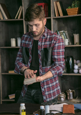 Young man leather maker packed in small cardboard box leather handmade wallet