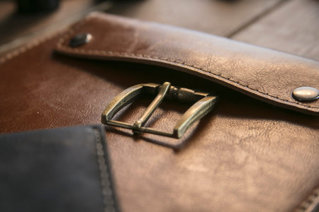 Close up of brown leather handmade handbag with bronze clasp on wooden table