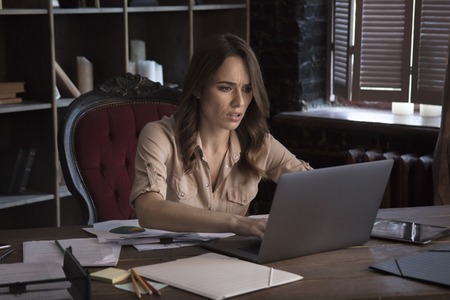 Young businesswoman working very hard with laptop sitting in office chairの写真素材