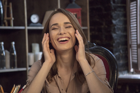 Young woman with long hair laughing with closed eyes and raised armsの写真素材
