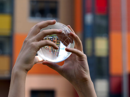 Children look at a transparent ball. The bowl is reflected beautiful new building. The concept -...