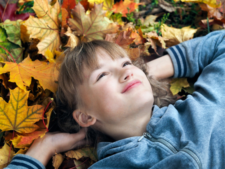 Portrait of a beautiful young teen girl with autumn leaves in the parkの写真素材