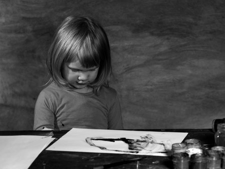 The grim. Black and white. Sad child next to a table with colors. Social photo. Loneliness, sadness, problems of children. The trouble is, indifferenceの写真素材