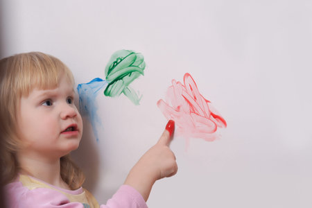 Small child draws a finger paints on a large white sheet of paper. Finger paint for the little children.の写真素材