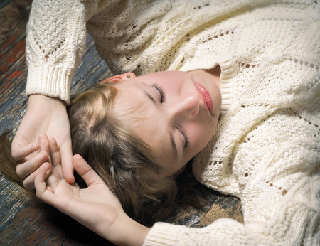 Beautiful young girl lying on the old wooden floor. The concept of relaxation, rest, reflectionの写真素材