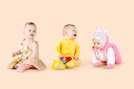 Babies on a beige background. Three children, different emotions and posesの写真素材