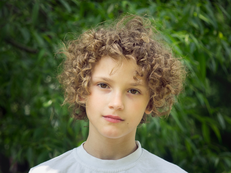 Portrait of a curly-haired baby on natural backgroundの写真素材