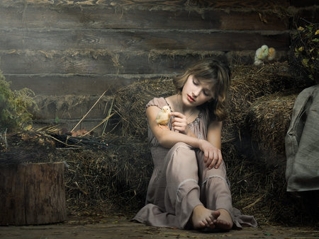 young girl with a newborn chick in the hayの写真素材