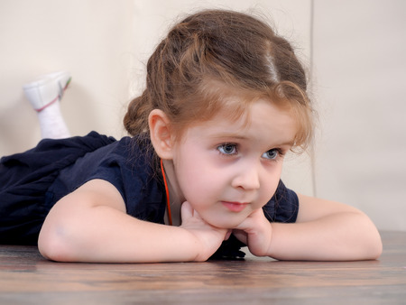 Portrait of a little girl. The child lies on the floorの写真素材