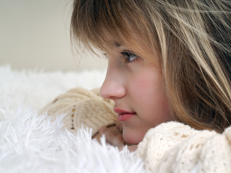 Portrait of a beautiful young girl. Face in profile. His hair was blond. The white fluffy plaidの写真素材