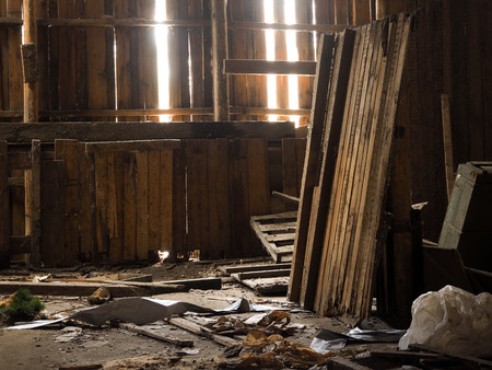 Rubbish, garbage in an old wooden barn. Rays of lightの写真素材