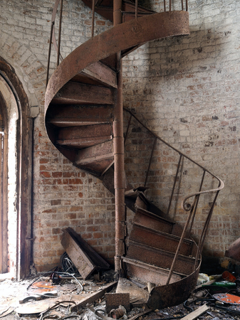 Rusty old staircase spiral. A lot of garbage. The brick walls of the towerの写真素材