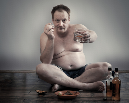 man with alcohol and a cigarette sitting on the floor. Habits, lifestyleの写真素材