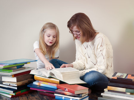 The children read a book. Large mountains of books around