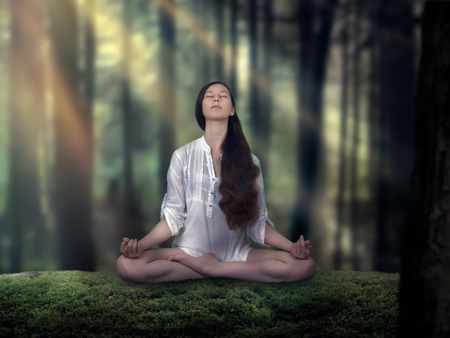 Beautiful girl doing yoga in the woods. Woman in Lotus position. The rays of the sunの写真素材