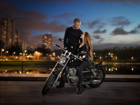 A guy, a girl and a motorcycle. The side of the road, the lights of the night city