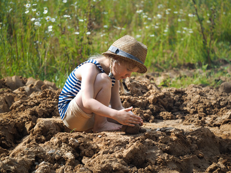 Little girl sculpts out of clay. A lot of dirt, funny babyの写真素材
