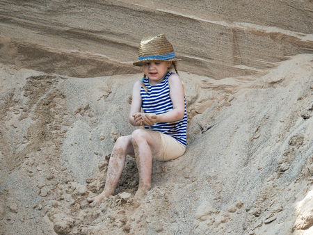 little girl playing on a mountain of sandの写真素材