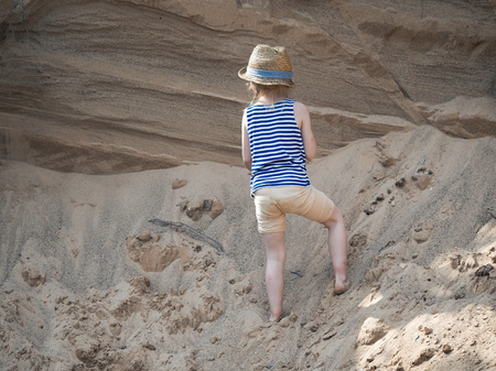 little girl playing on a mountain of sandの写真素材