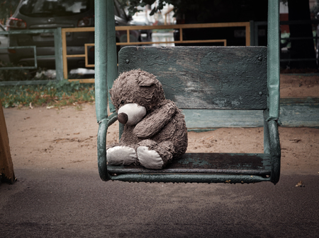 Miserable wet Teddy bear on a swing in the rainの写真素材