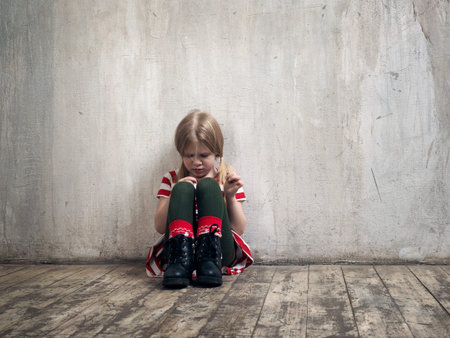Sad little girl sitting on the floor. The concept of child psychology, loneliness, resentmentの写真素材