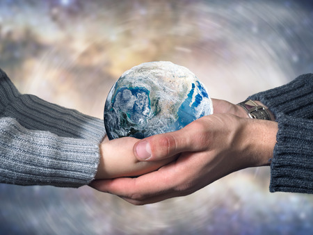 Freezing planet Earth. Hands of an adult and a child. The concept of climate change, ice age, abnormal weather on the planetの写真素材