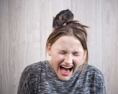 The girl in panic shouting. On her head sits a rat. The concept of a phobia, a fear of rodents, inner fears, hallucinationsの写真素材