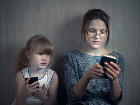 A small child and the teenager with smartphonesの写真素材