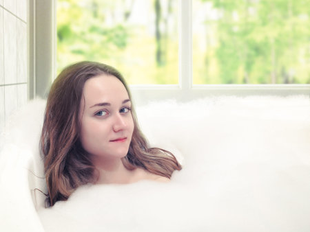Portrait of young woman with bubble bath and window with nature view