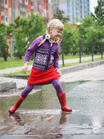Happy baby jumping on puddles in the cityの写真素材