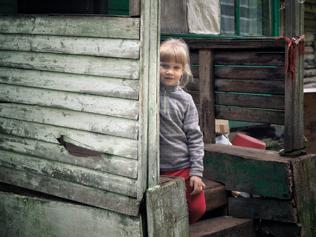 Portrait oPortrait of a village little girl. The porch of the old housef a village little girl. The...