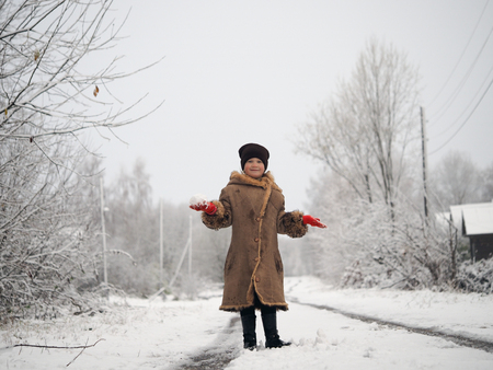Portrait of a cheerful girl with a snowball in her handsの写真素材