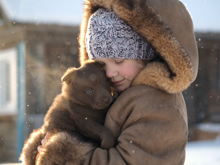Cute little girl with a wonderful puppy in her arms. Snow, winter. Portrait of a child with a dogの写真素材