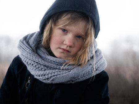 Portrait of a discontented , tired child in warm clothes