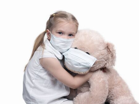 A child in a medical mask hugs a large toy bear.の写真素材