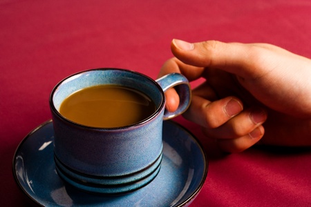A hand holds a ceramic coffee mug.の写真素材