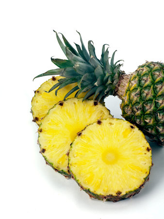 Three pinapple rings fanned out next to the green leafy top