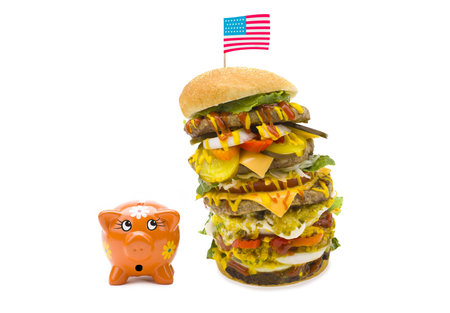 An enormous burger with many layers topped with the American flag.の写真素材