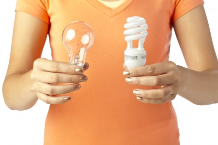 Close up image of human hand holding two different kinds of light bulbs against white backgroundの写真素材