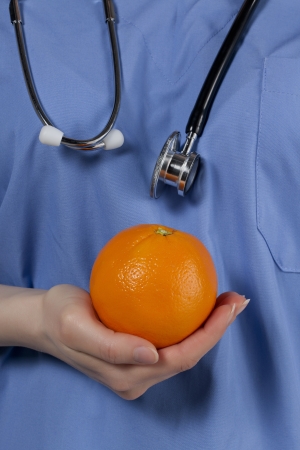 Close-up image of a nutritionist holding orange fruitの写真素材